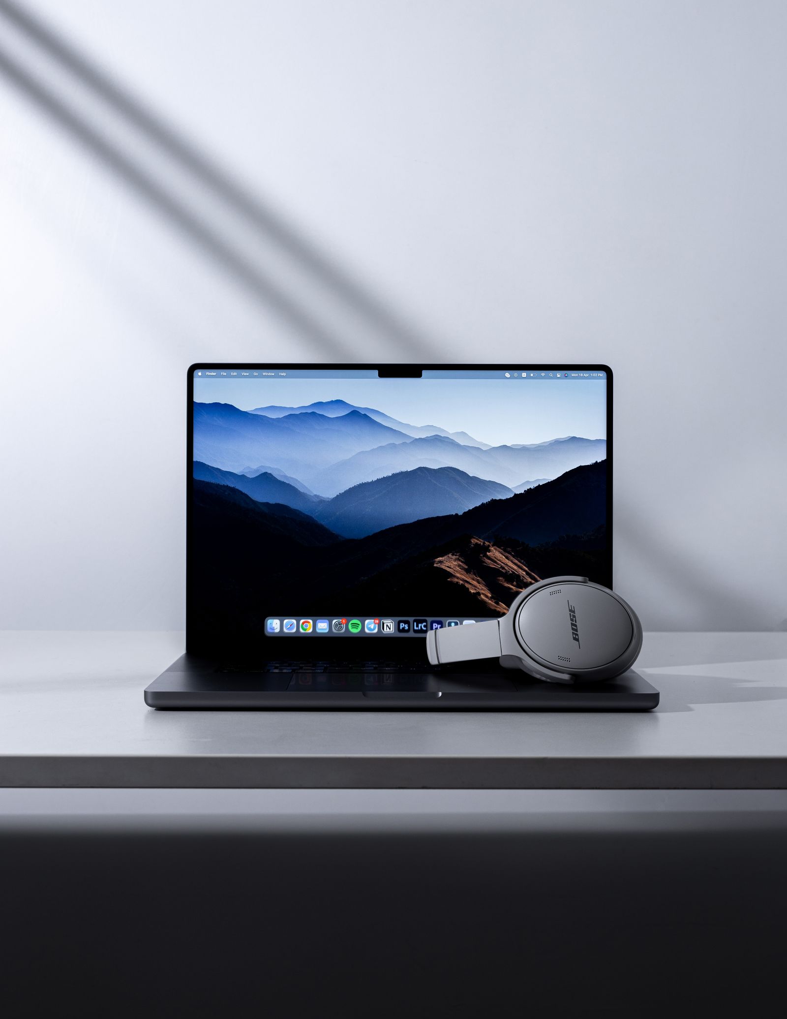 Laptop và tai nghe trên bàn, màn hình hiển thị hình nền phong cảnh.