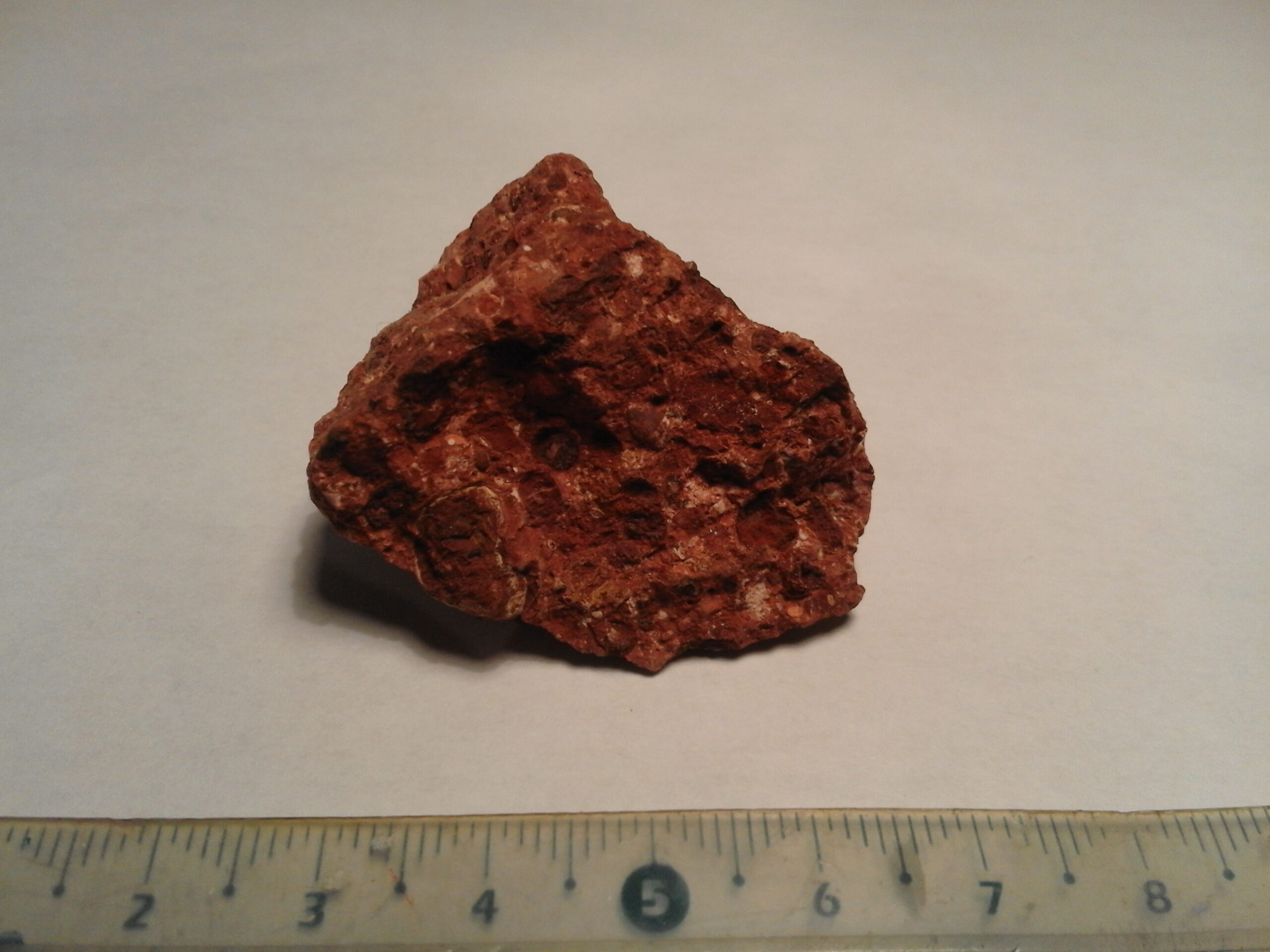 Mẫu quặng bauxite màu nâu đỏ từ Hérault, Pháp, có thước làm mốc kích thước.